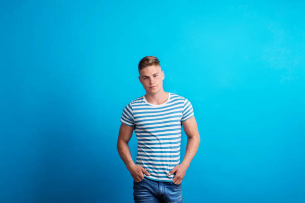 istock Portrait of a young man in a studio standing against blue background. 1047028046