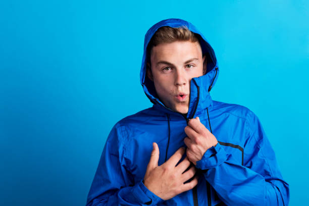 istock Portrait of a young man with blue anorak in a studio, feeling cold. Copy space. 1047028160