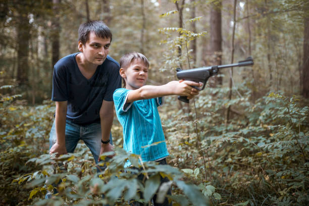 istock Man Teaches boy How To Shoot From Air Gun 1047038704