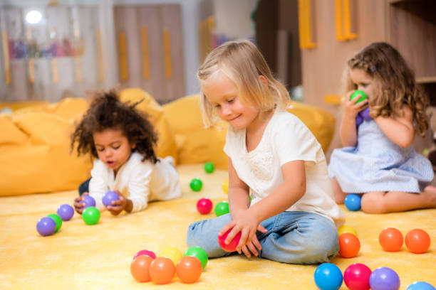 istock adorable multicultural kids playing with colored balls on floor in kindergarten 1047041684