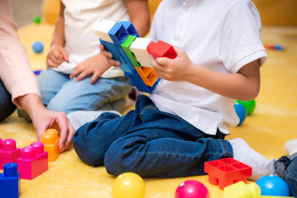 istock cropped image of tutor and kids playing with constructor in kindergarten 1047041750