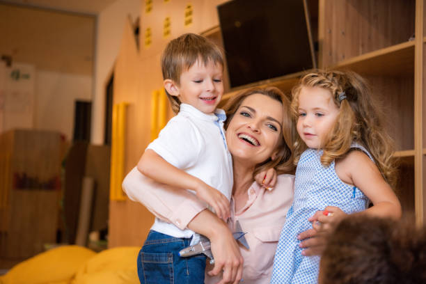 istock happy educator hugging adorable smiling kids in kindergarten 1047041810
