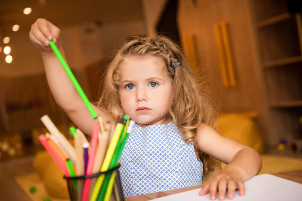 istock adorable kid taking green felt tip pen for drawing in kindergarten 1047041844