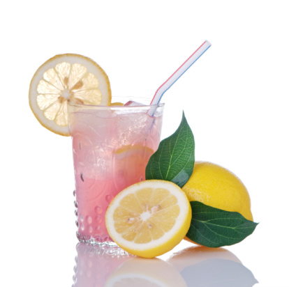 Glass of pink lemonade and lemons with leaves