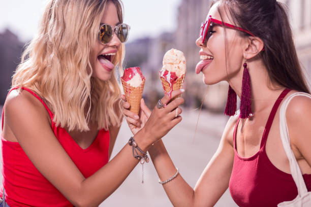 istock Joyful happy women trying each others ice cream 1047066174