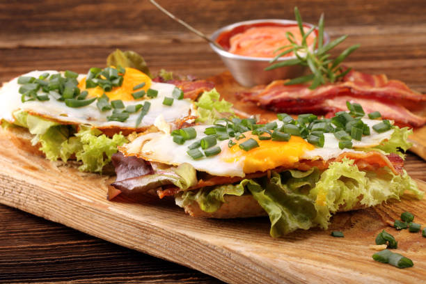 istock Fried eggs with bacon and chives on wooden background 1047076706
