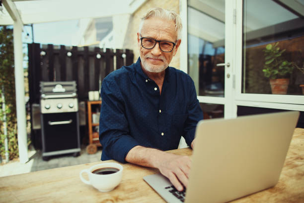 istock Smiling senior man enjoying a coffee and working online outside 1047081182