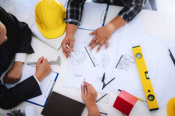 gens d’ingénieur réunion travail et pointant à un dessins au bureau pour discuter. outils d’ingénierie et construction concept. - général photos et images de collection