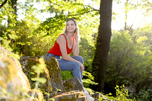 laughing young woman with sunglasses sitting in the park