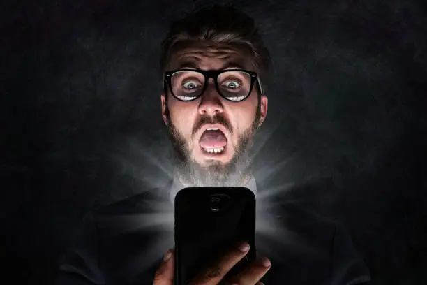 Photo of Nerd with glasses is shocked after reading a sms