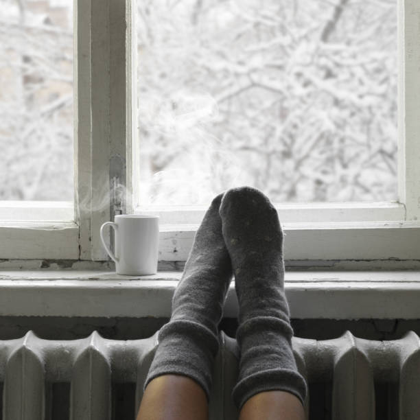 Cozy winter still life Cozy winter still life: woman feet in warm woolen socks and mug of hot beverage on old windowsill against snow landscape from outside. hygge photos stock pictures, royalty-free photos & images