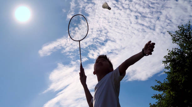 istock Asian boy practicing his badminton serve in a hot sunny day. 1047099504
