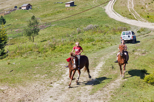 MIKULICZYN, UKRAINE - SEPTEMBER 14, 2018: Young riders horsemen gallop across the Starishora mountain valley, Carpathian Mountains.