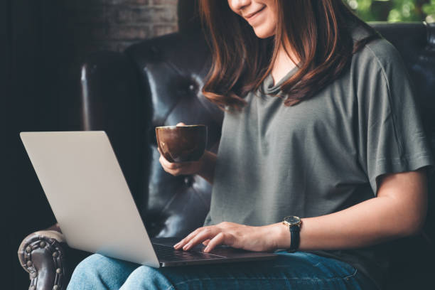 istock Closeup image of a woman working , using and typing on laptop keyboard while drinking coffee 1047111776