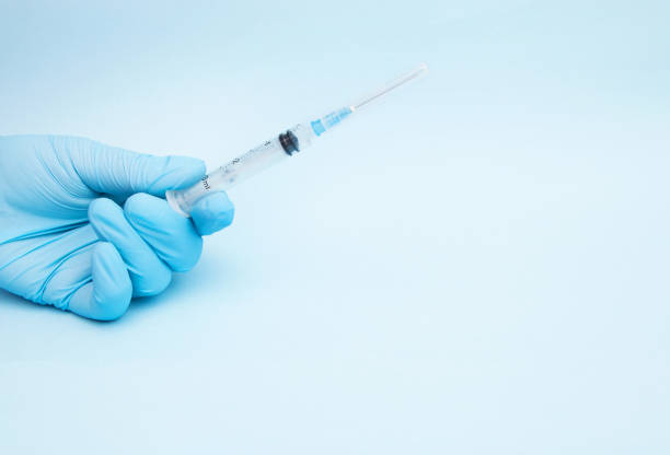 istock Female hand holding syringe with blue background 1047119002