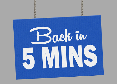 Cardboard  back in 5 minutes sign hanging from ropes. Clipping path included so you can put your own background