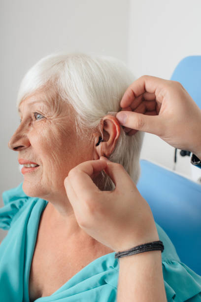 istock Cropped doctor's hand applying hearing aid for an aged woman 1047136834