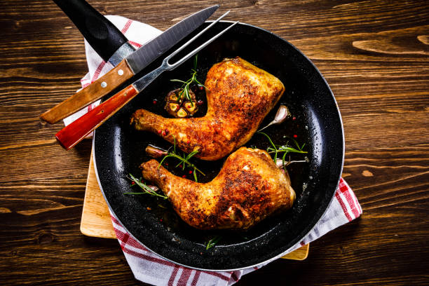 Fried chicken legs in pan on cutting board on wooden background