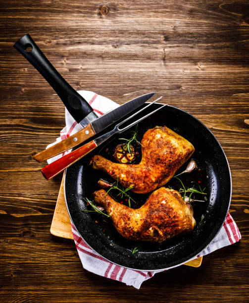 istock Fried chicken legs in pan on cutting board on wooden background 1047142638