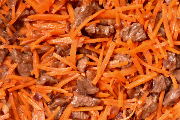 Roasting vegetables and meat in a frying pan with non-stick coating. Onion, carrots and meat