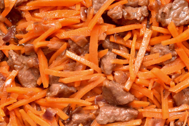 Roasting vegetables and meat in a frying pan with non-stick coating. Onion, carrots and meat