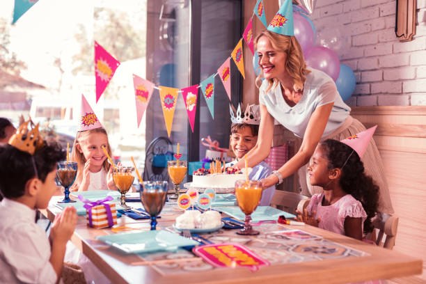 All children smiling while kind mother bringing birthday cake