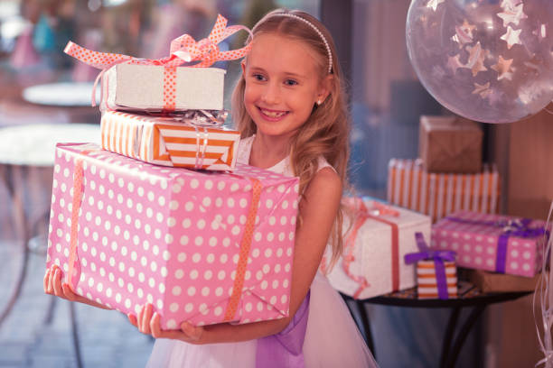 istock Emotional birthday girl smiling while holding three big presents 1047163552