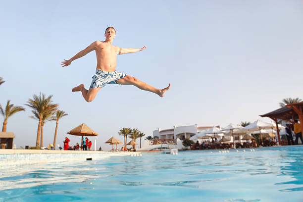 Man jumping in swimming pool stock photo