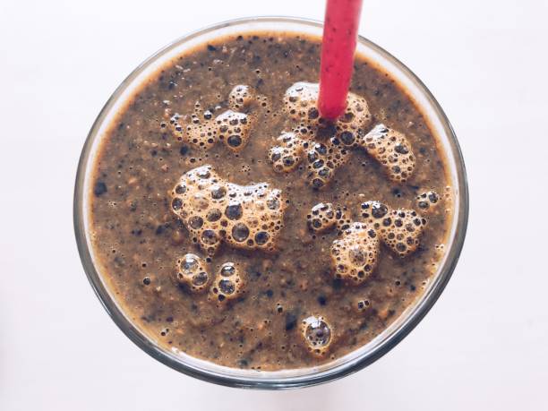 Fresh from the tap nitrous infused dark rich nitro black coffee in a glass jar java creamy beautiful froth foam head lifestyle decor with roasted beans on a rustic reclaimed wood wooden table background