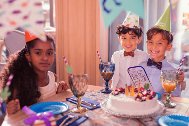 istock Happy friends enjoying dinosaur party and smiling while sitting with cake 1047182948