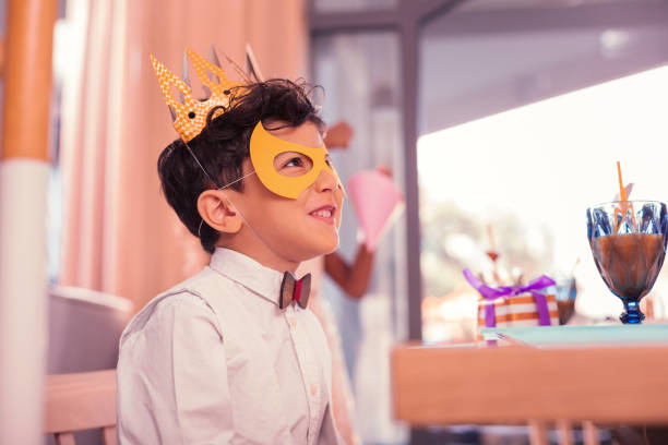 istock Cheerful boy wearing mask and paper crown while visiting carnival 1047182958