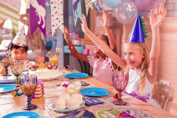 istock Excited kids putting hands up and dancing at the table 1047183008