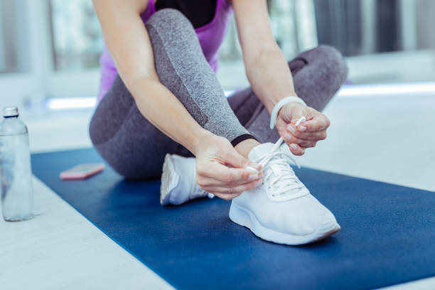 istock Smooth female hands tying shoelaces before workout 1047196538