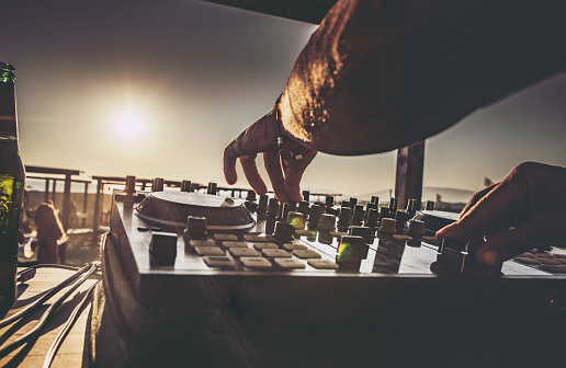 Close up of a DJ playing music on the beach at sunset.
