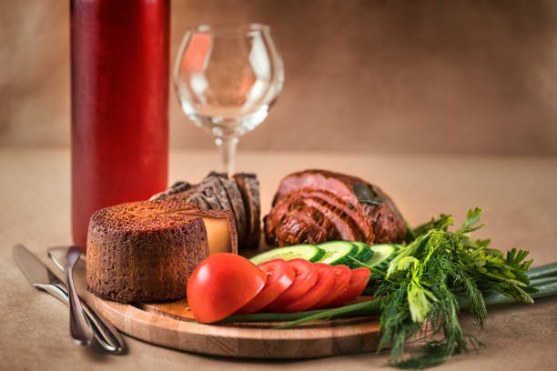 Still life with food and drink. Ham, cheese, vegetables and red wine on craft background