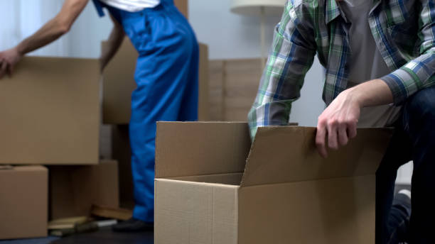 istock Man unboxing things in new apartment, moving company worker bringing boxes 1047207532