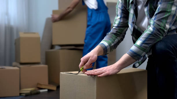 istock Man unpacking things in new apartment, moving company worker bringing boxes 1047207534