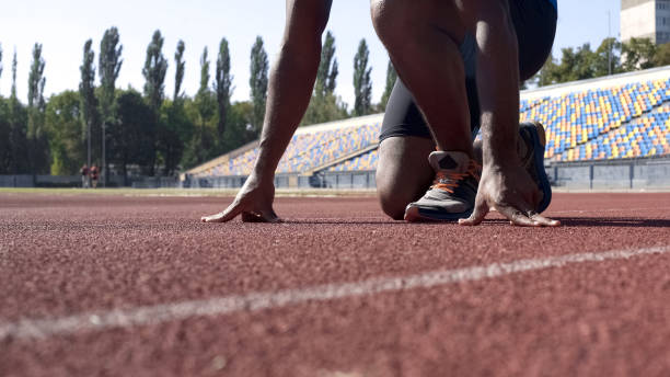 istock Man in starting position on track, professional runner training at stadium 1047207754