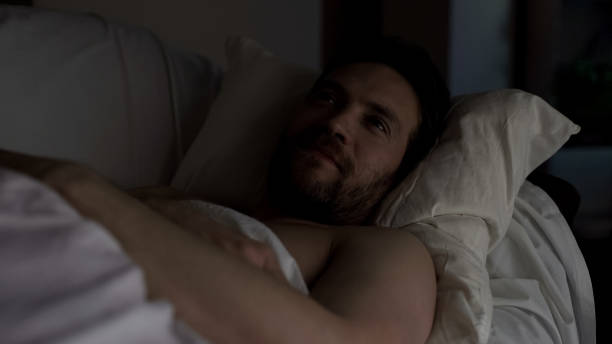 istock Man lying in bed, having some pleasant thoughts and smiling, nostalgic memories 1047211778