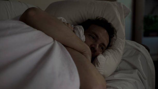 istock Depressed man lying in bed unable to fall asleep, noisy neighbors, insomnia 1047212448