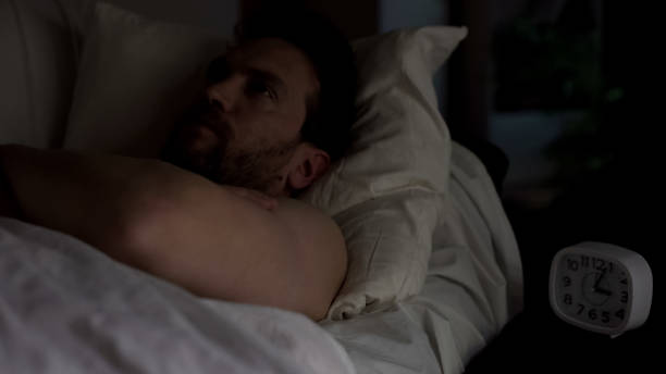 istock Displeased man lying in bed unable to fall asleep, looking at ceiling, insomnia 1047212458