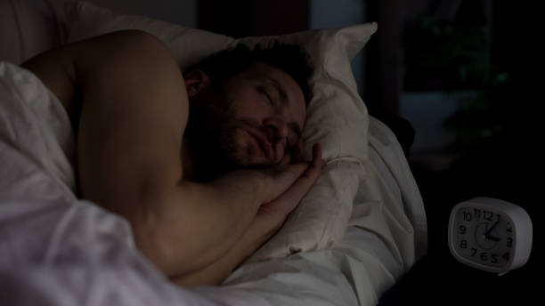 istock Calm man sleeping on sofa, clock standing on night table, late night rest 1047212474