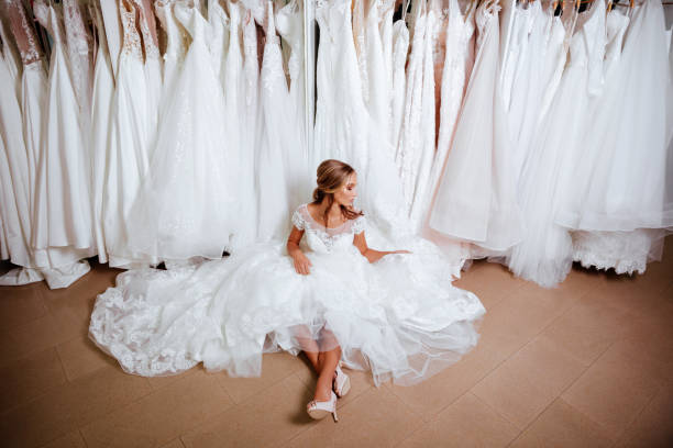 séduisante jeune mariée est souriant tout en choisissant la robe de mariée - wedding bride buying caucasian photos et images de collection