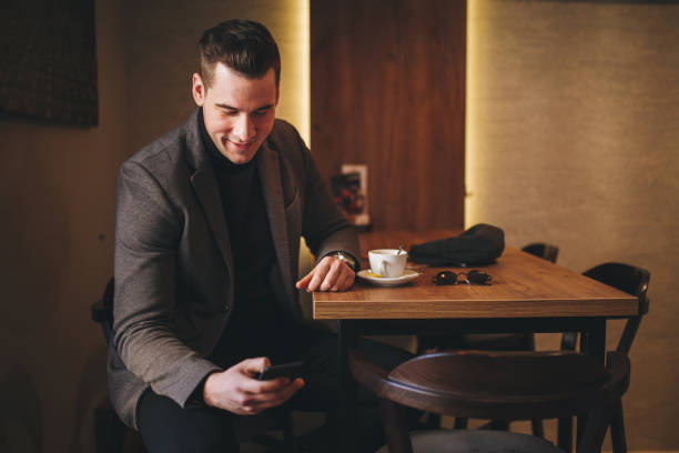 istock Handsome smiling businessman texting at a cafe 1047215988