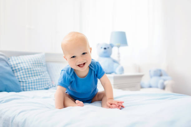 Little baby boy on white bed Adorable baby boy in white sunny bedroom. Newborn child relaxing in bed. Nursery for young children. Textile and bedding for kids. Family morning at home. New born kid during tummy time with toy bear. bear stomach stock pictures, royalty-free photos & images