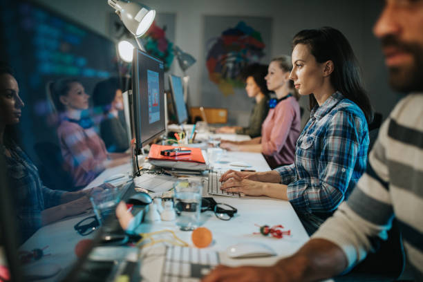 istock Concentrated female programmer working late with her colleagues in the office. 1047226734