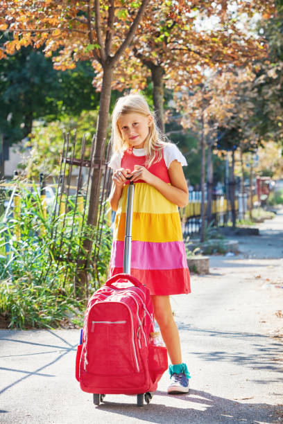 mignon de 8 ans écolière carry sac à dos à roulettes - female 8 9 years child excitement photos et images de collection