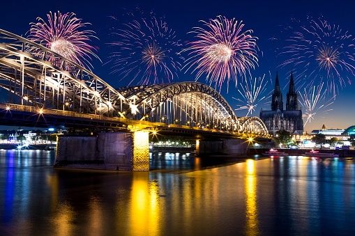 Fireworks light up the sky over Cologne, Germany.  \nThis is a HDR shot looking over the Rhine River towards the cathedral and centre of the city.