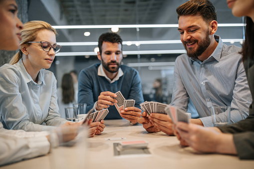 A man's hand holding a pair of playing cards with stack casino chips and revealed cards on a surface