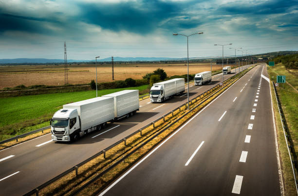 caravan or convoy of white lorry trucks on highway - convoy imagens e fotografias de stock